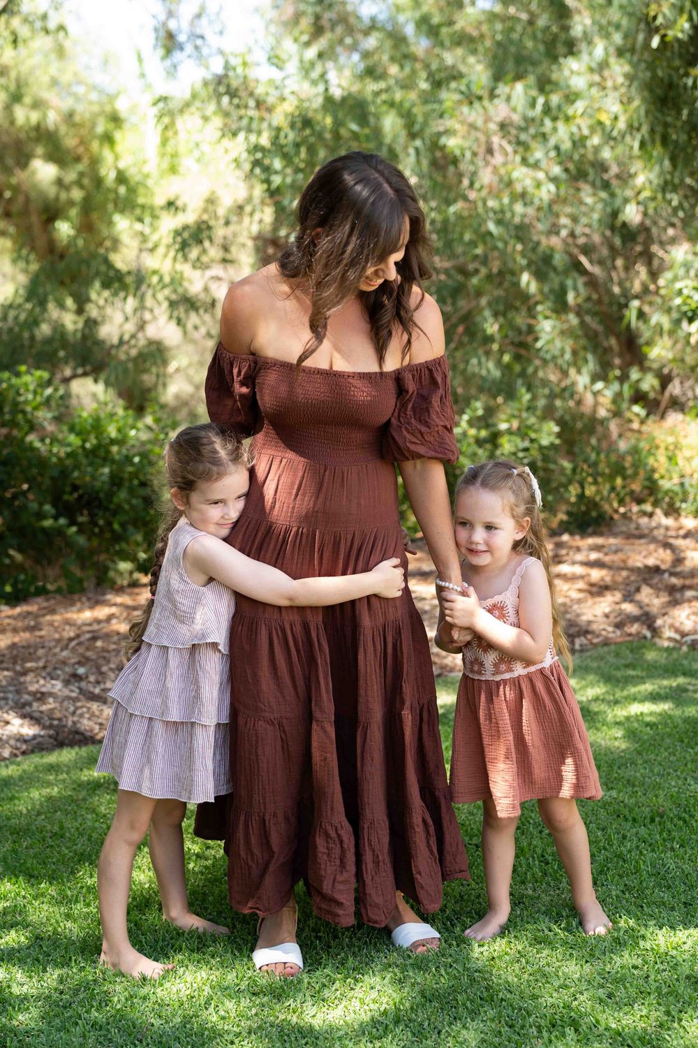 Two young children hugging their mother during an outdoor family photography session in Perth