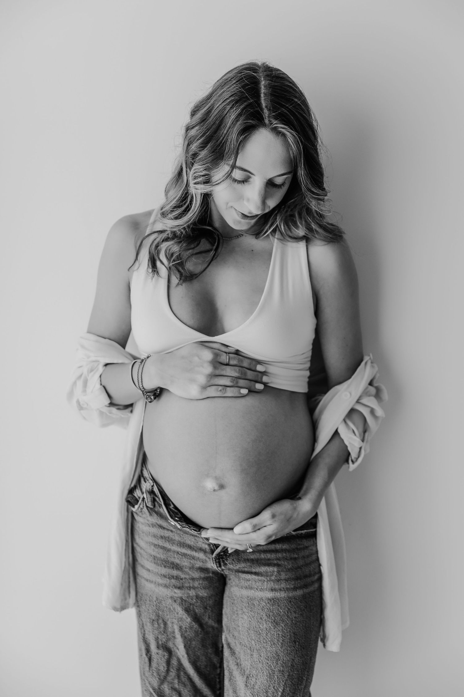 Black and white photo series showing a person in jeans and tank top touching their stomach in various intimate poses.