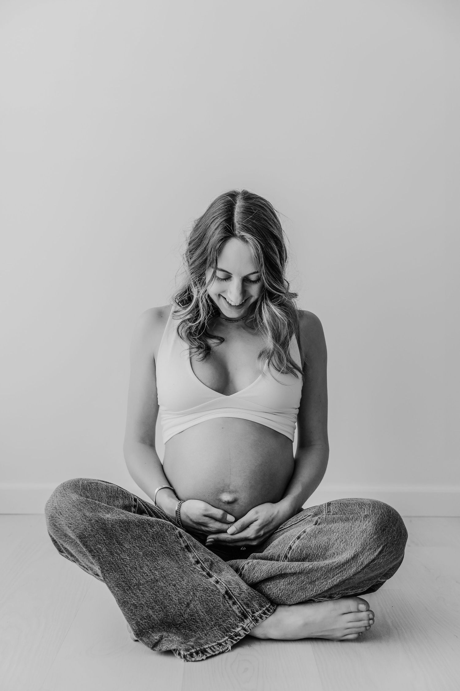 A series of minimalist black and white photographs showing a seated figure in jeans and white top against a plain background.
