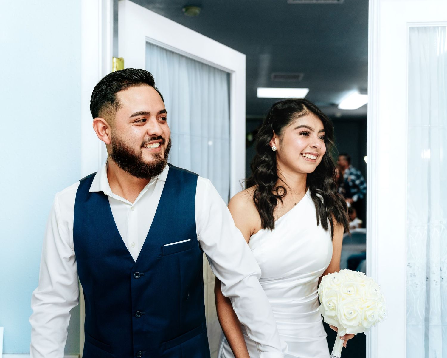 A happy couple shares a candid moment together while dressed in wedding attire with white hydrangea bouquet.