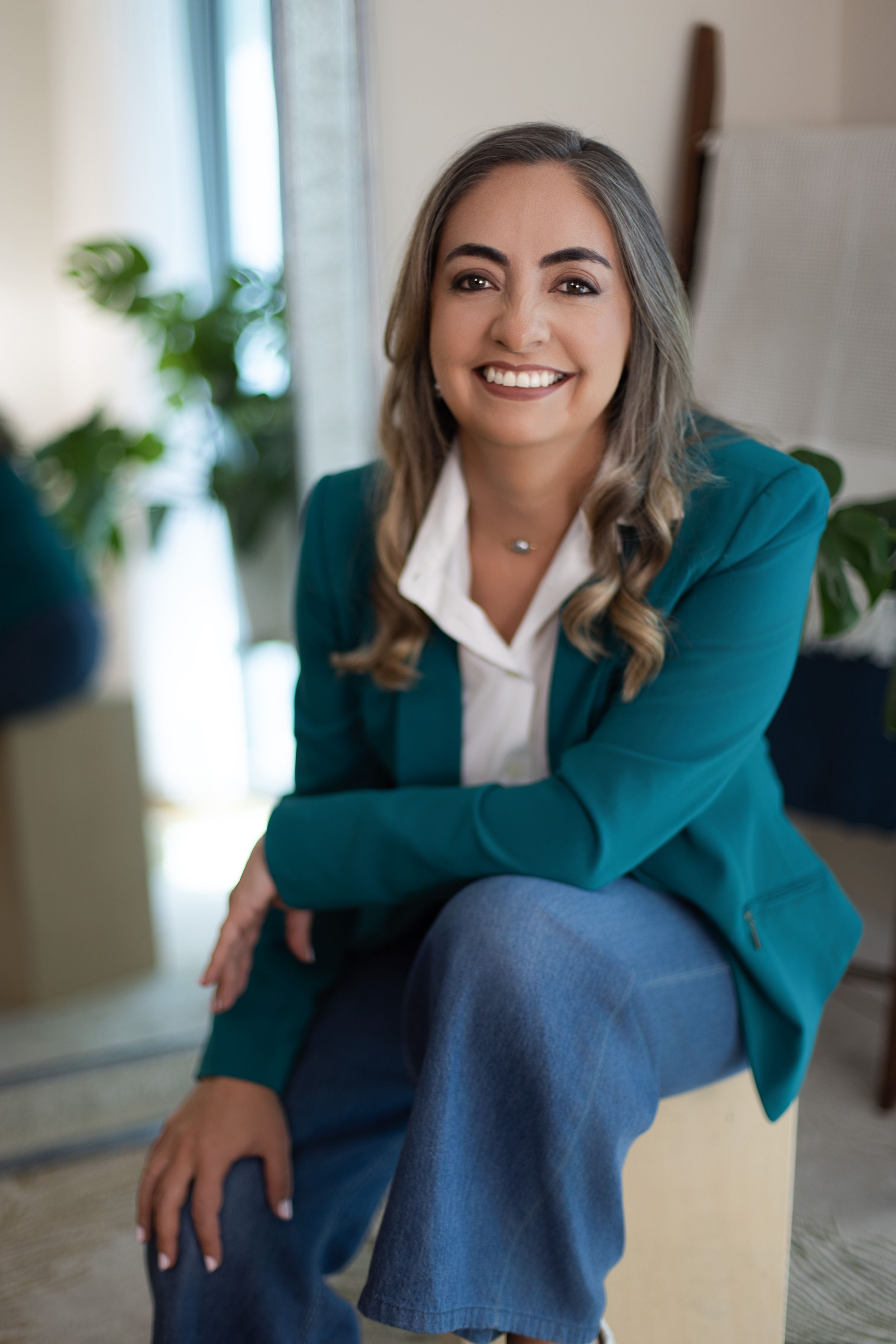 Professional headshots showing someone in a teal blazer and white blouse against a soft interior background.