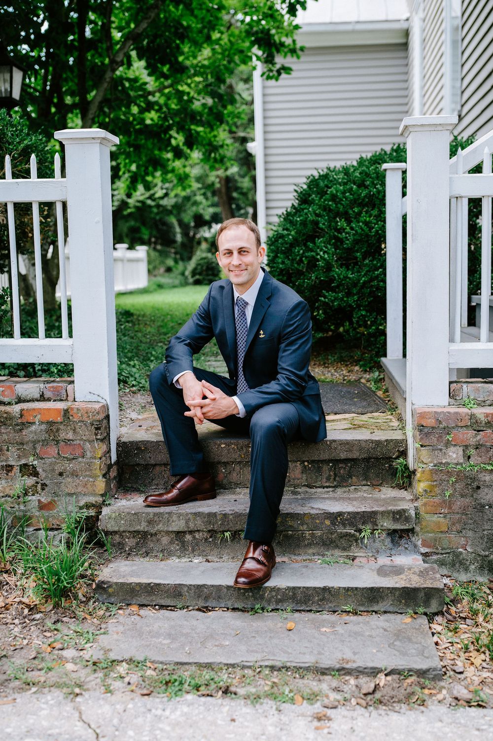 Three sequential photos show someone sitting on brick steps in a navy suit with brown shoes outside a white house.