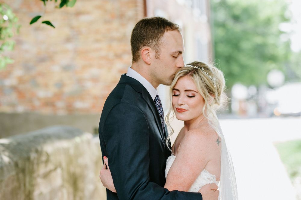 A couple in wedding attire share intimate moments in a romantic outdoor garden setting with brick walls.