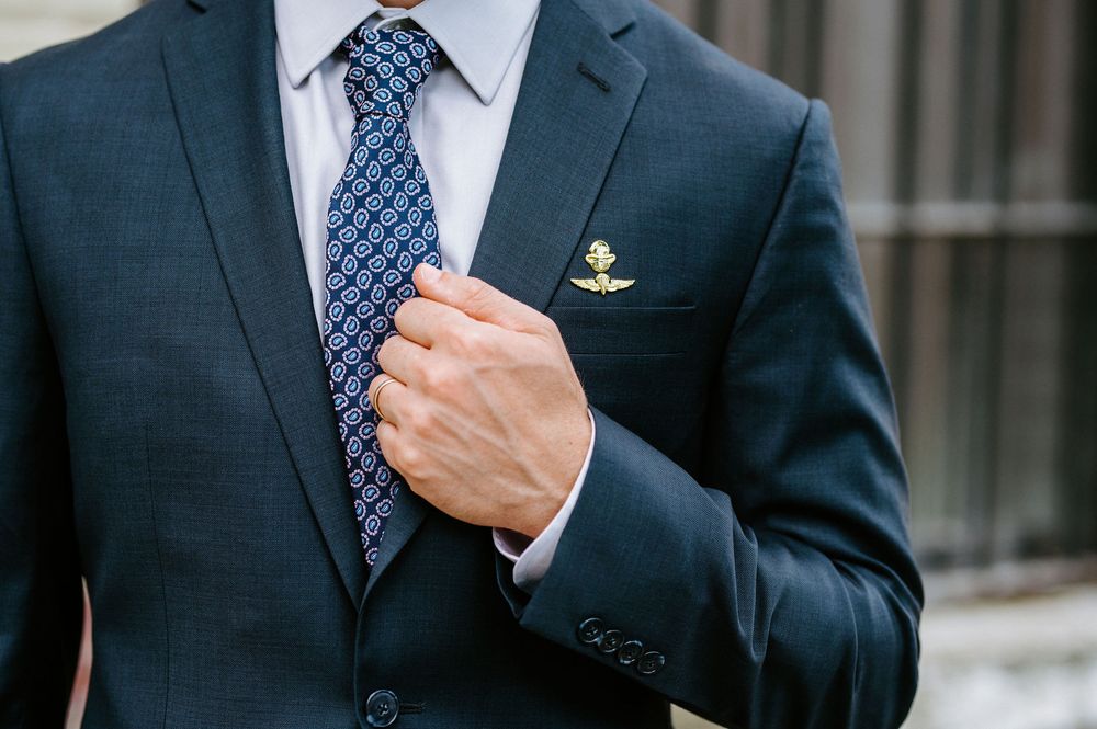 Close-up view of a navy suit jacket with blue polka dot tie and white dress shirt.