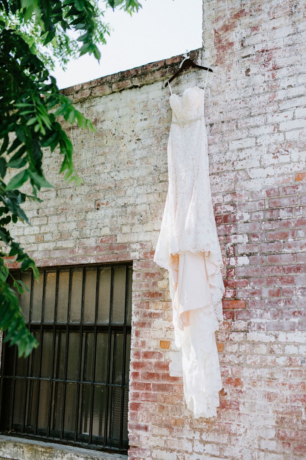 White fabric hanging from brick wall creates ghostly silhouette against weathered red brick and black window bars.
