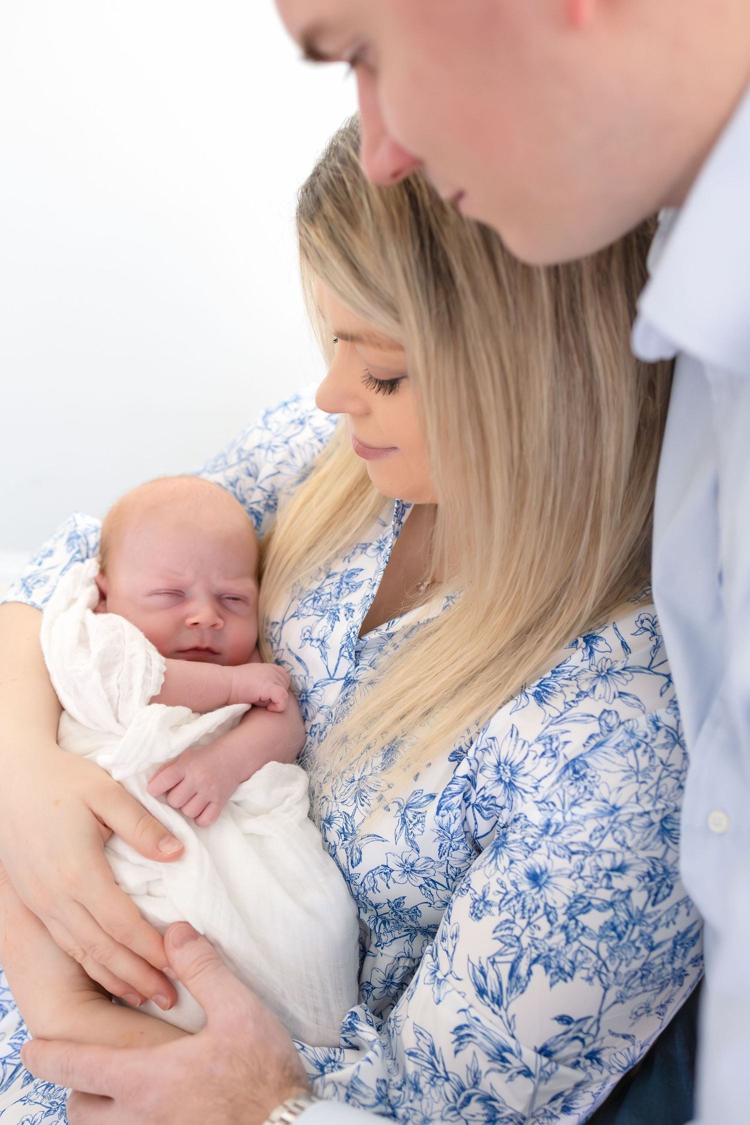 Mom & dad holding their newborn baby near window light during North Georgia lifestyle newborn photography session.