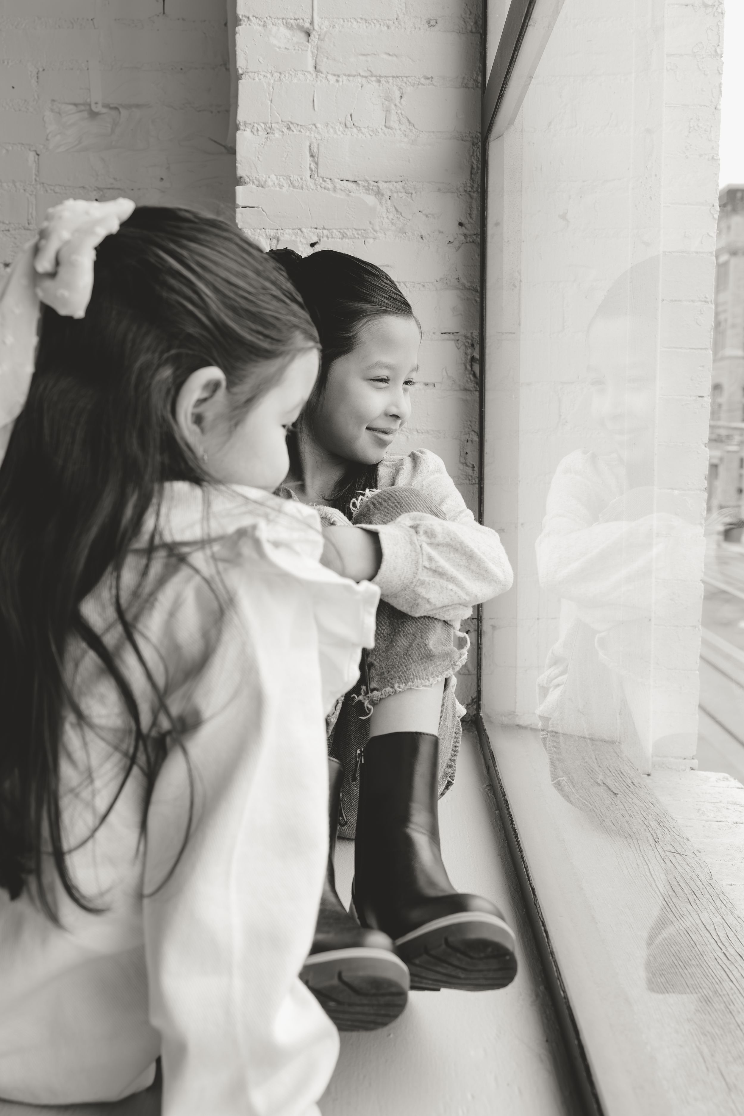 A series of black and white photos showing a person in a white sweater leaning against a white brick wall.