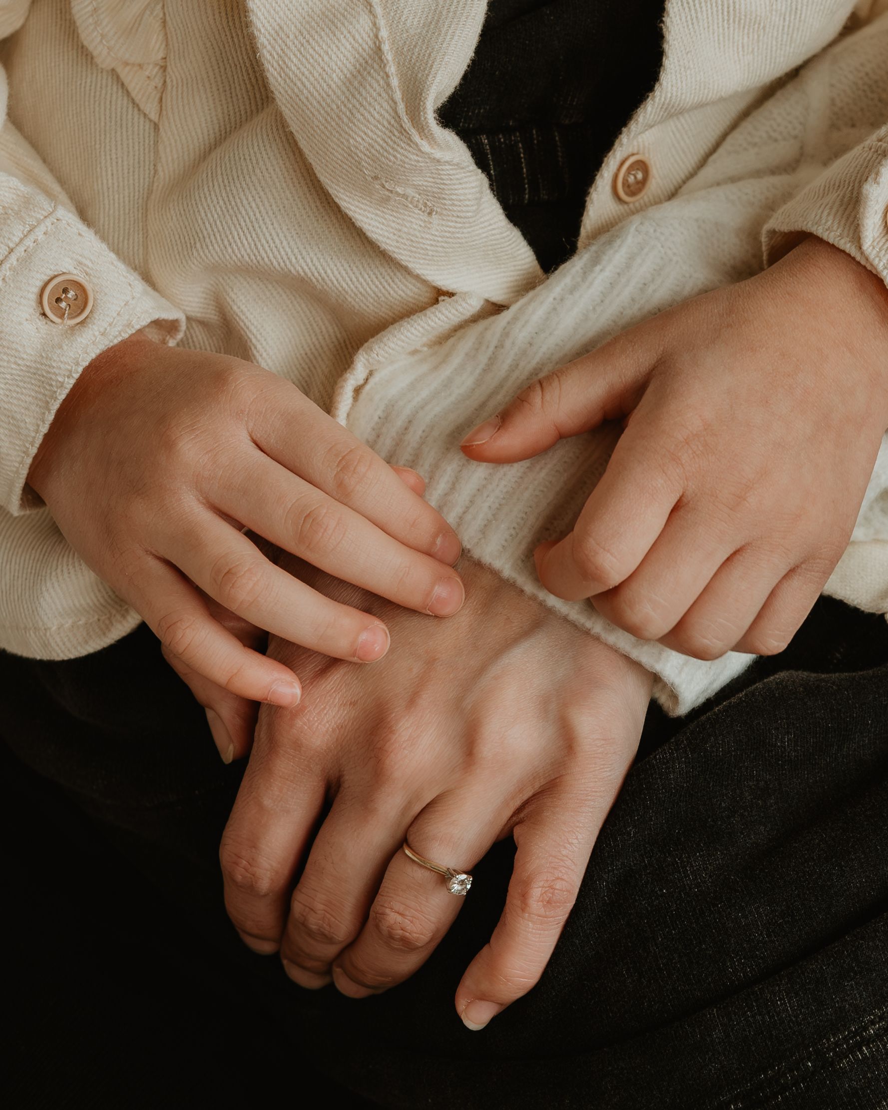 A series of hands wearing gold rings shown against a dark background, creating an artistic composition.