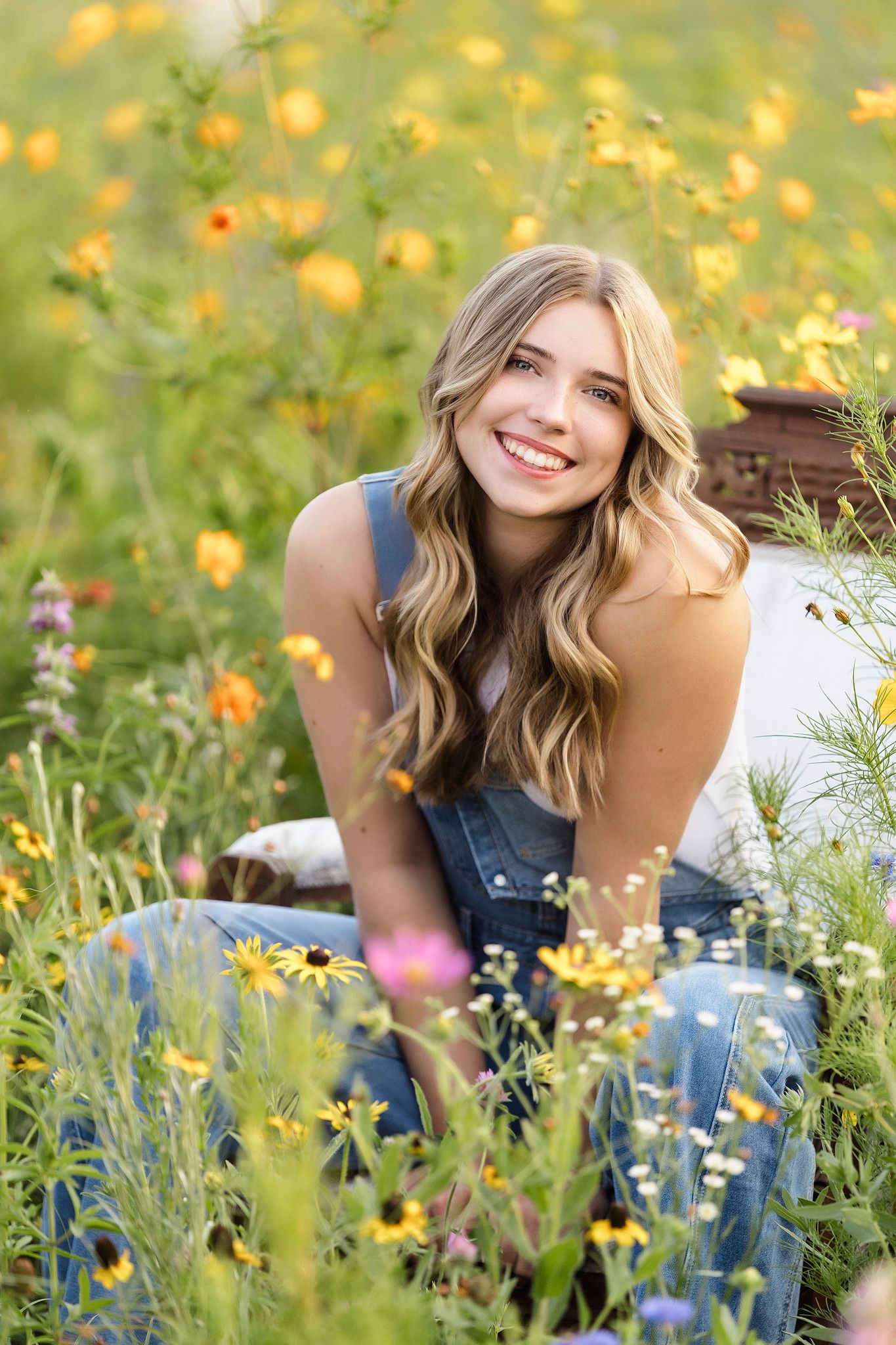 A person lays in a vibrant wildflower meadow filled with yellow blooms and blue flowers on a sunny summer day.
