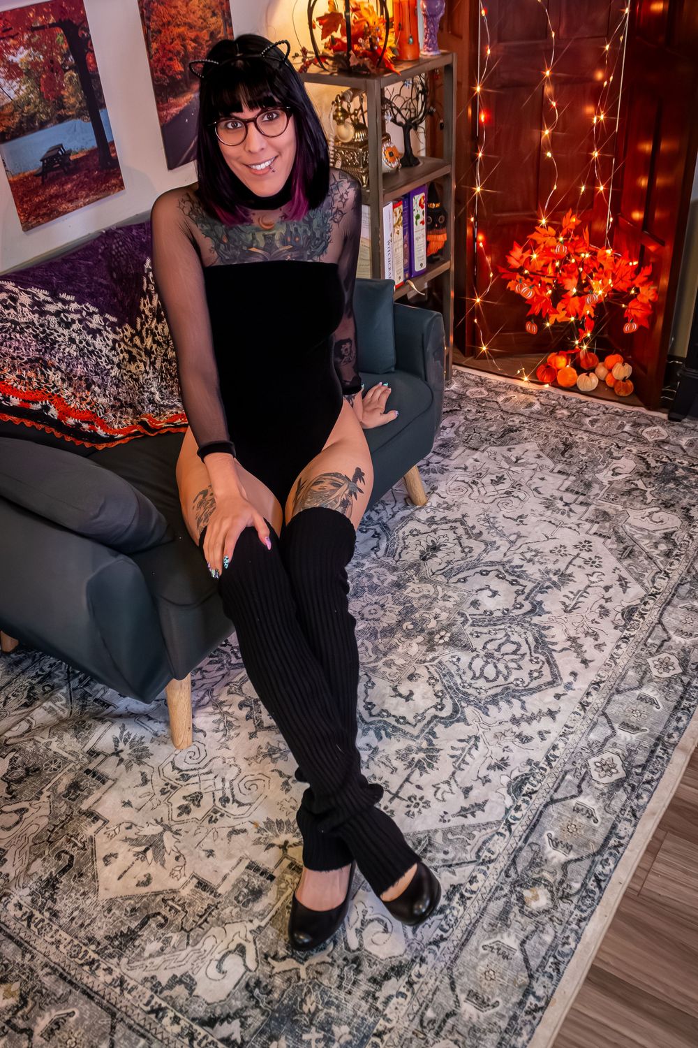 Someone sits on a patterned rug with string lights and artwork visible in the background.