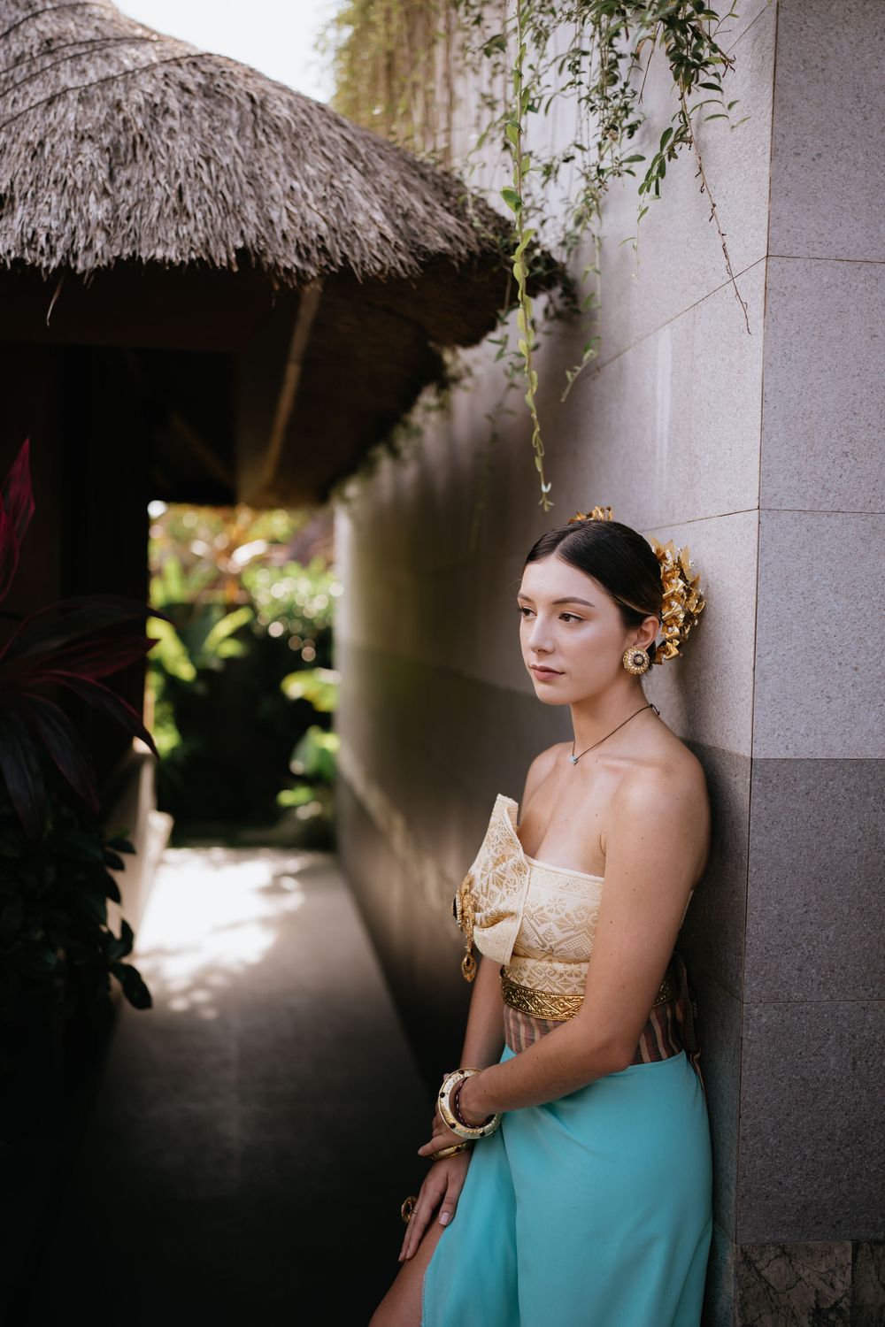 Elegant portrait under thatched roof with cream corset and turquoise sarong.