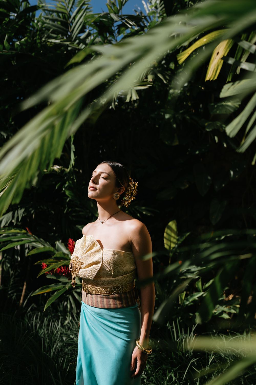 Tropical fashion shoot among palm fronds with traditional inspired clothing.