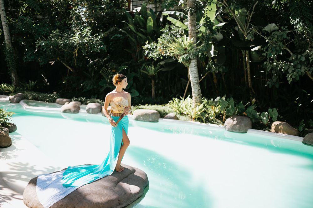 Artistic poolside photo featuring traditional Thai costume against a lush tropical garden backdrop.