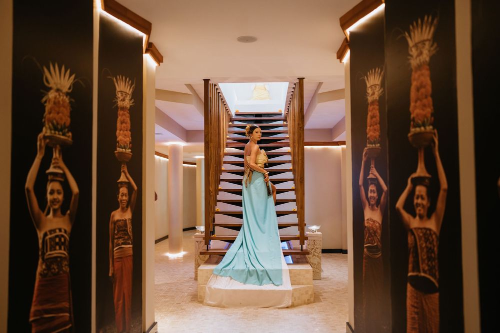 Dramatic photo in a hallway with decorative wall panels and a sweeping turquoise gown.