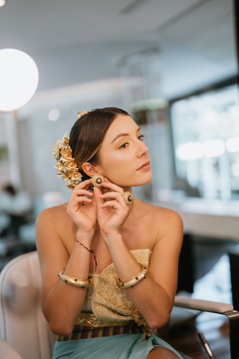 Close-up portrait showcasing ornate gold hair accessories and traditional Thai-inspired styling.
