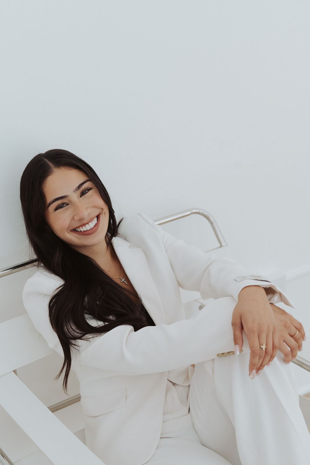 Professional wearing crisp white suit poses against clean white background.