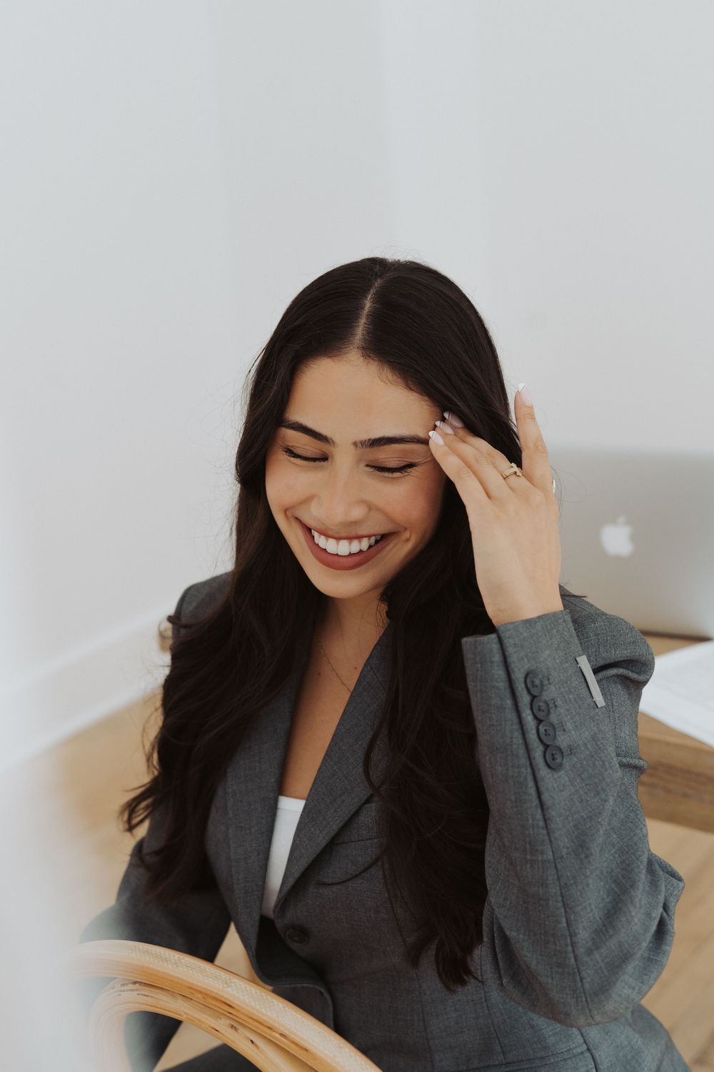 Professional in grey blazer smiling during business photoshoot.