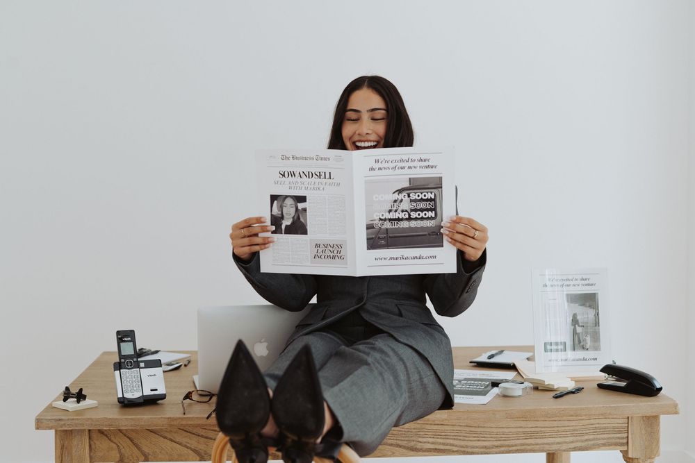 Business professional reviewing documents at wooden desk against white wall.