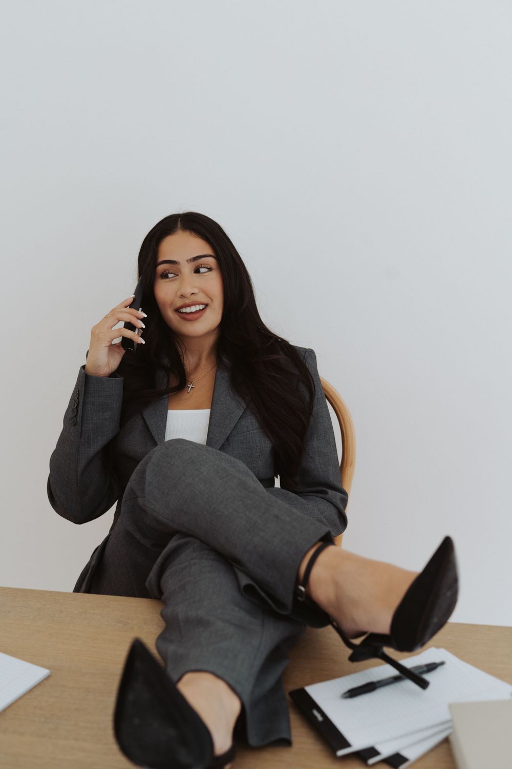 Professional in grey suit relaxing on white couch during business photoshoot.