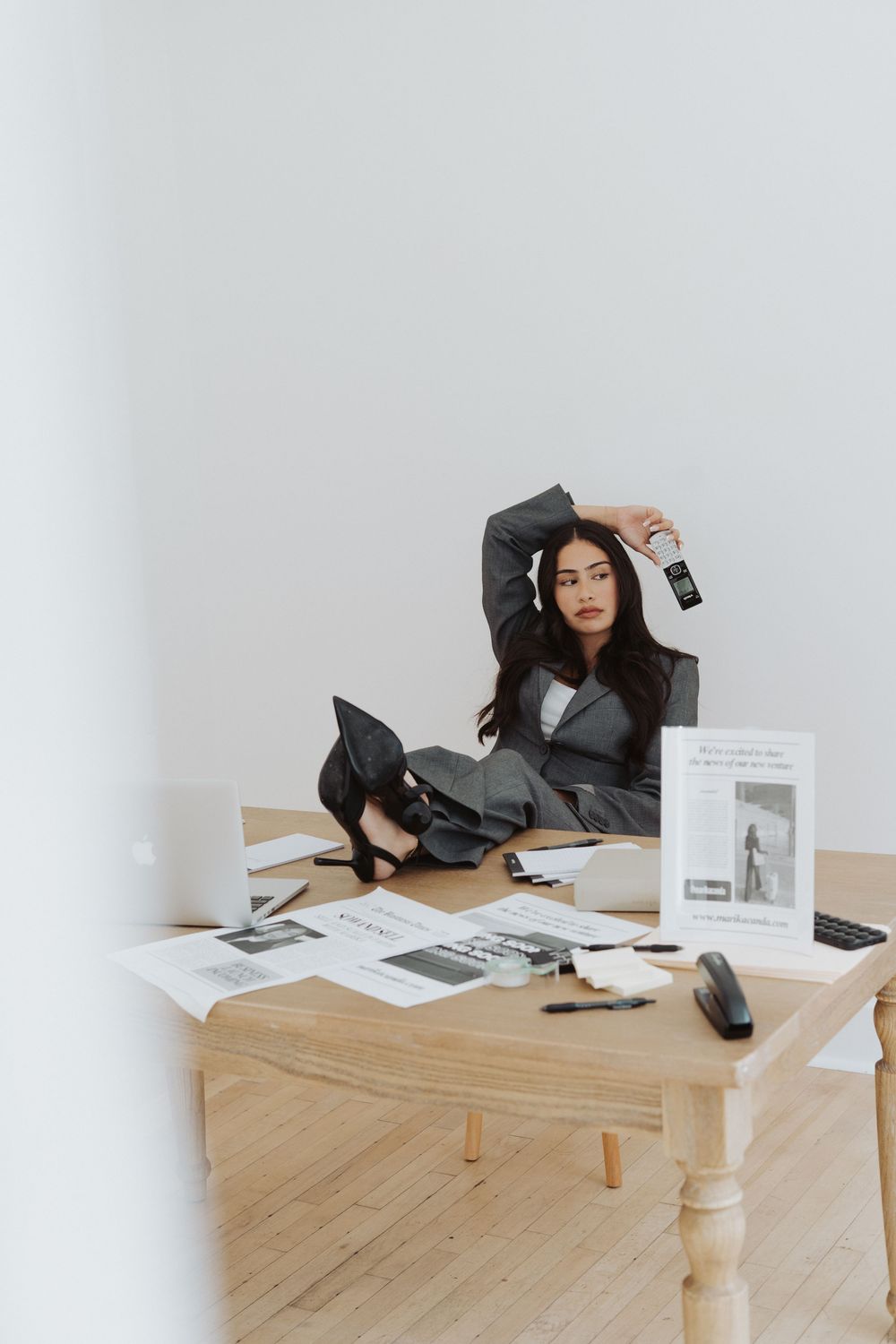 Professional workspace setup with scattered papers on wooden table against white wall.