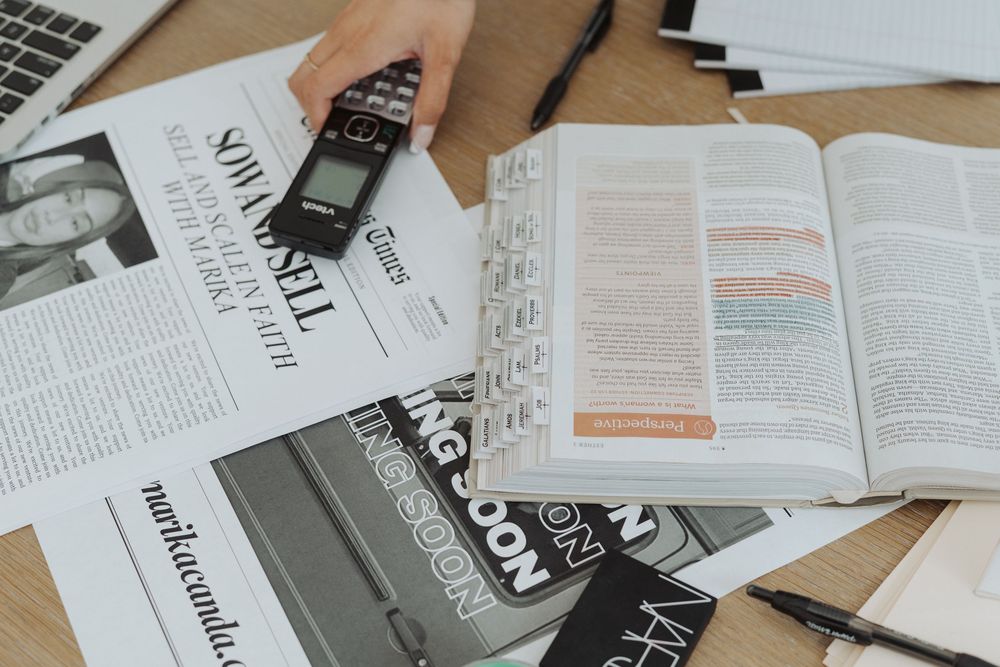 Papers and documents scattered across a wooden desk showing business planning materials.
