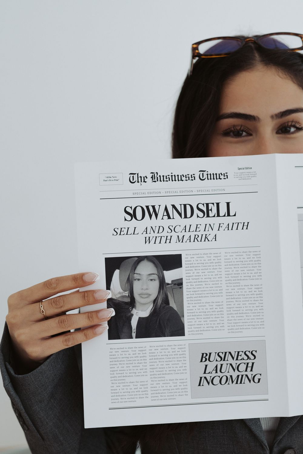 Hands holding up a business newspaper with headlines about selling and scaling.
