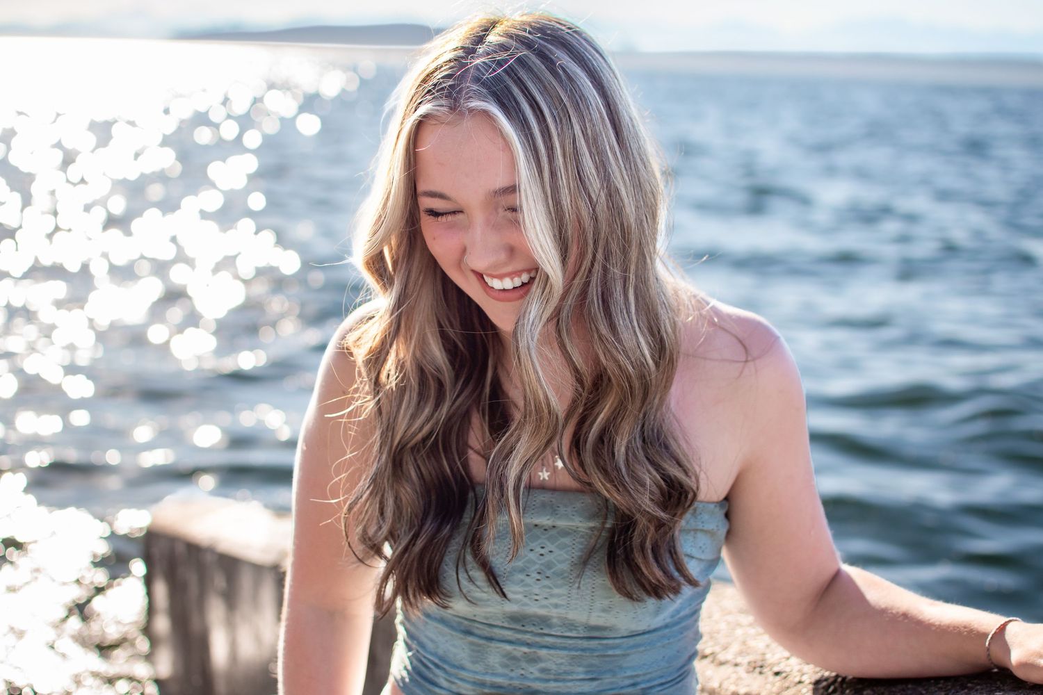 Senior laughing by the water at Alki Beach in Seattle during a fun and relaxed senior session.