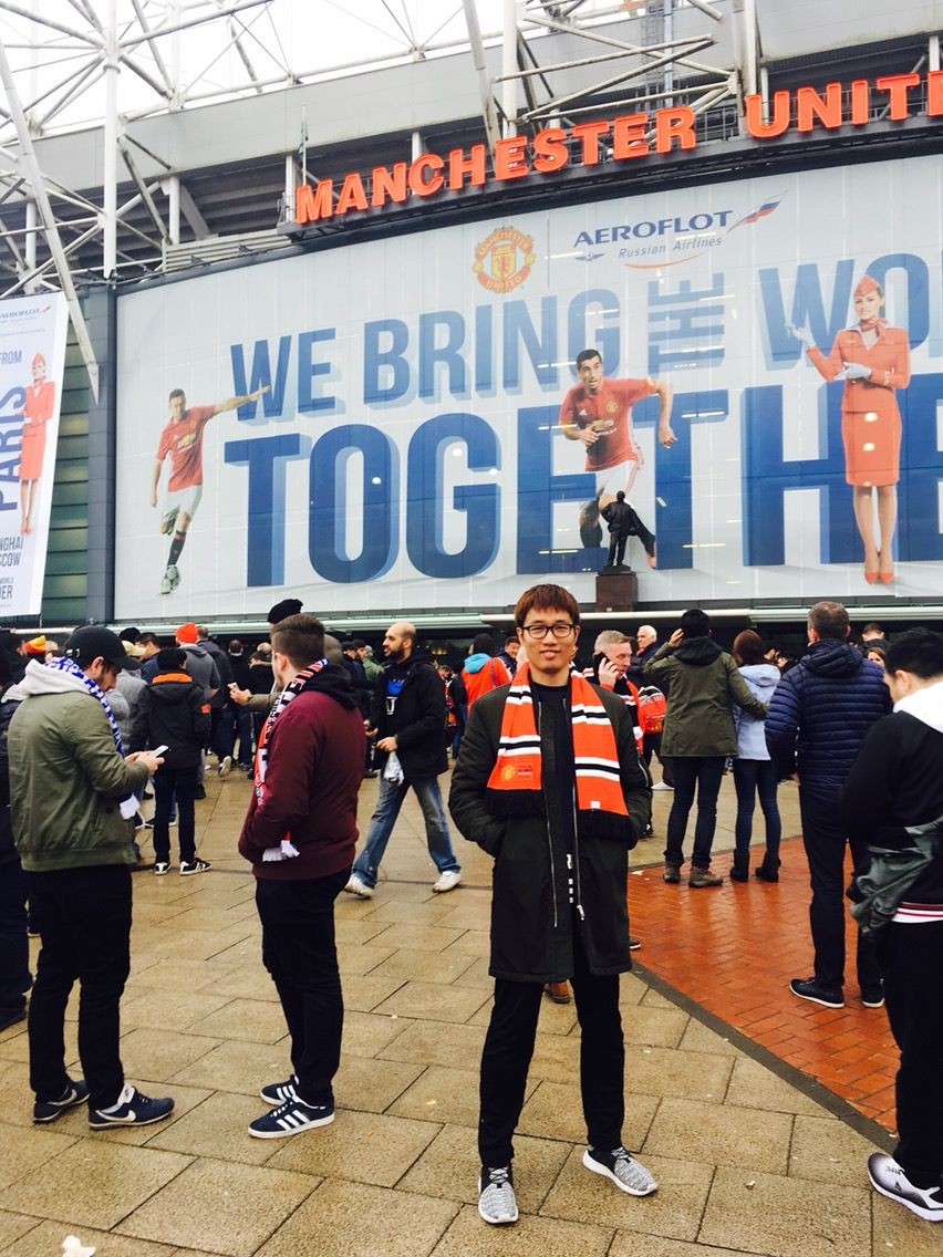 People lined up in a stadium concourse with orange banners and "WE BRING" signage visible on the walls.