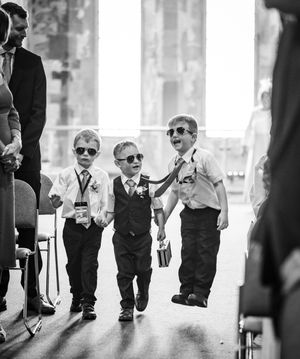 Group of young attendants in matching black vests walk together at the wedding venue.
