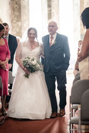 A traditional church wedding processional shows a bride in white gown walking down the aisle.