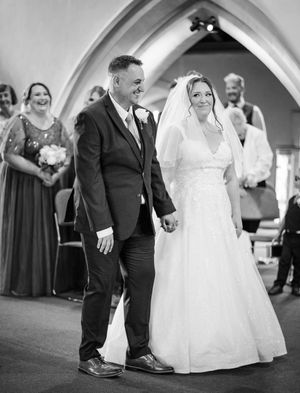 A joyful moment captured in black and white as wedding couple walks together in a church with arched ceilings.
