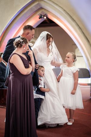 A series of candid moments at a wedding showing people in brown and white dresses interacting in an arched interior.