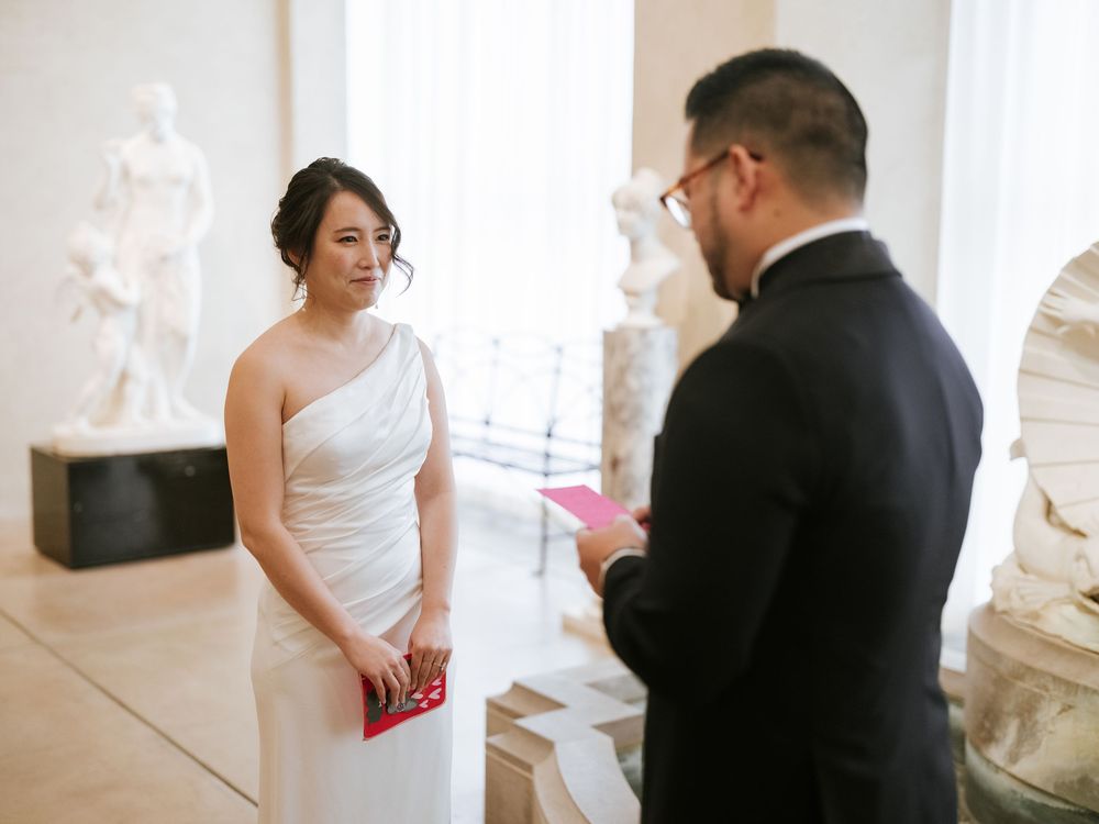 A bride and groom share an intimate moment during their first look in a bright, sunlit room.