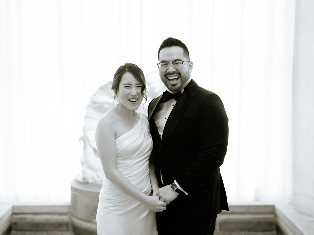 A couple shares joyful laughter in a bright, minimalist setting during their wedding photoshoot.