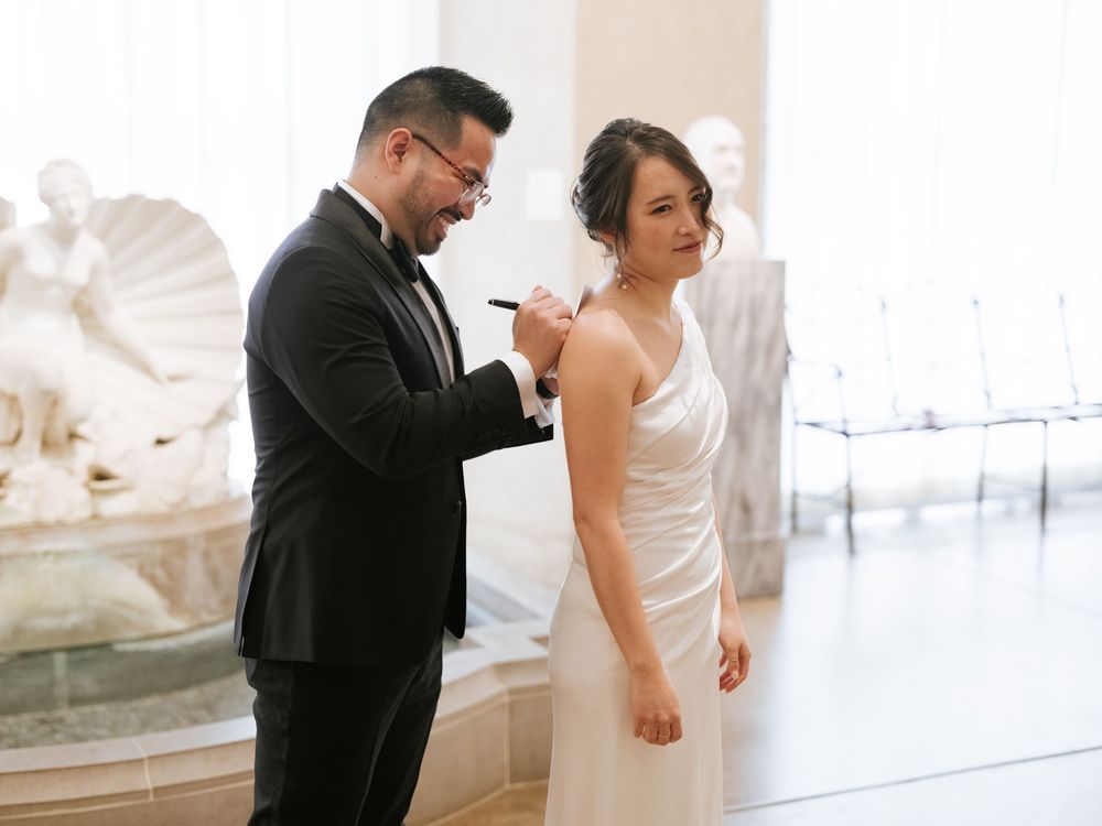 A couple shares an intimate first look moment at their wedding in an elegant white venue.