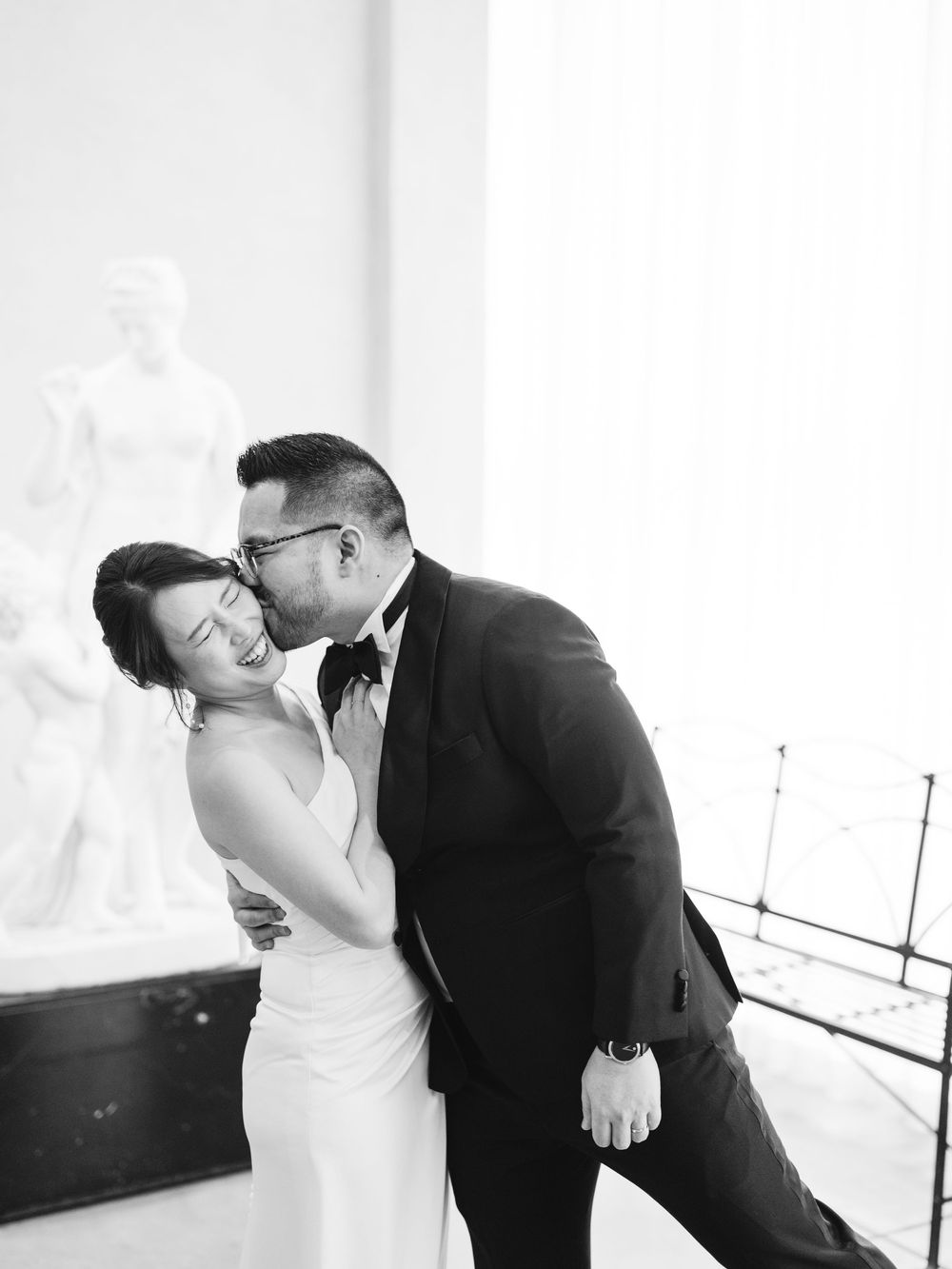 A romantic black and white wedding photo shows a couple sharing an intimate moment in formal attire.