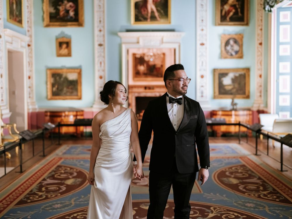 Couple shares an intimate dance moment in an ornate gallery with classical portraits and elegant decor.