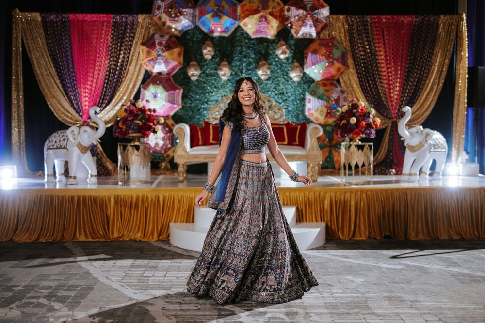 Dancers in traditional Indian attire perform graceful movements during a cultural celebration on an illuminated stage.