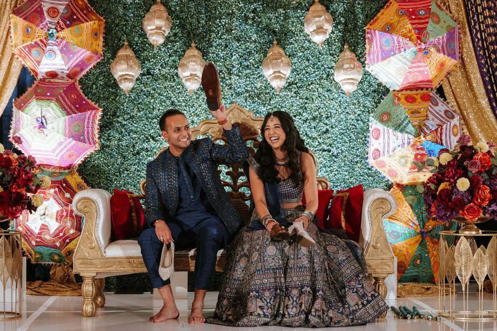 Wedding reception venue decorated with pink paper umbrellas and glittering green backdrop for photo opportunities.