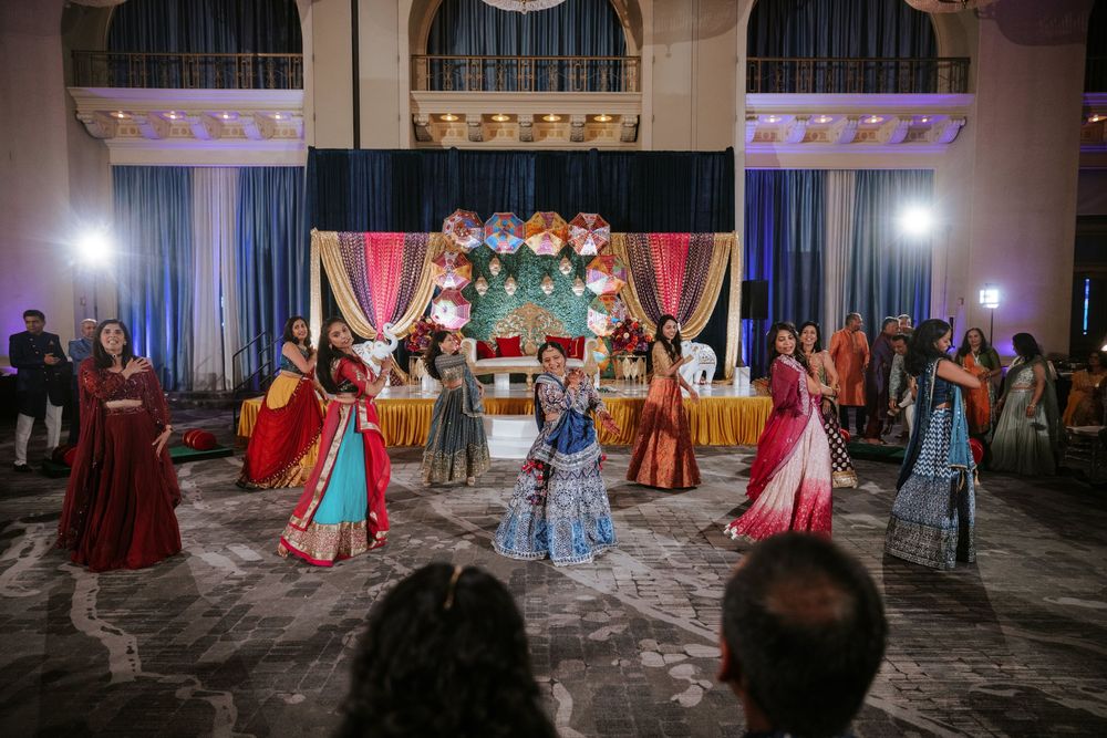Guests dancing and celebrating at a vibrant Indian wedding reception with colorful decorations and lighting.