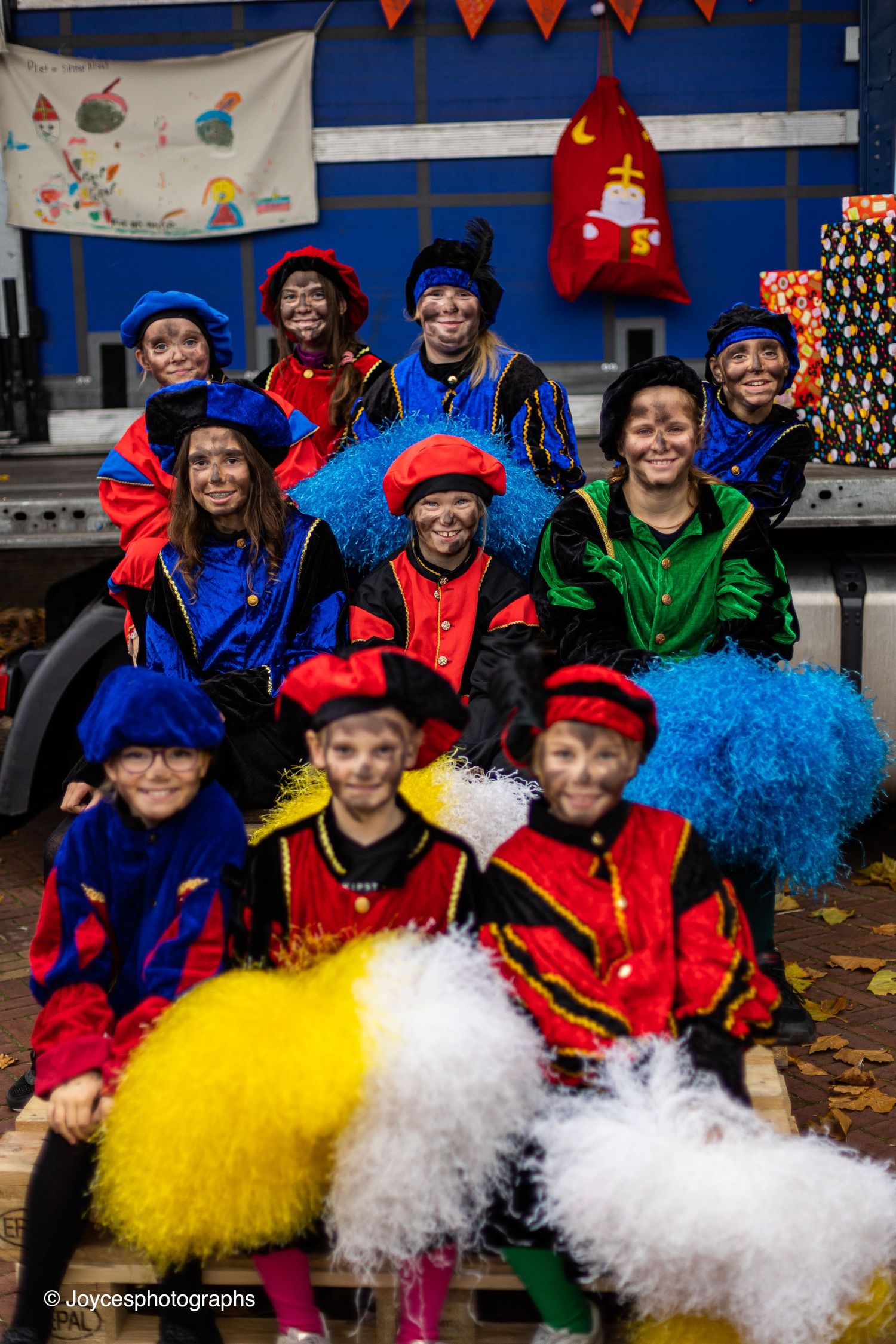 Performers in colorful costumes with blue, red, and yellow tutus pose together during a festive celebration.