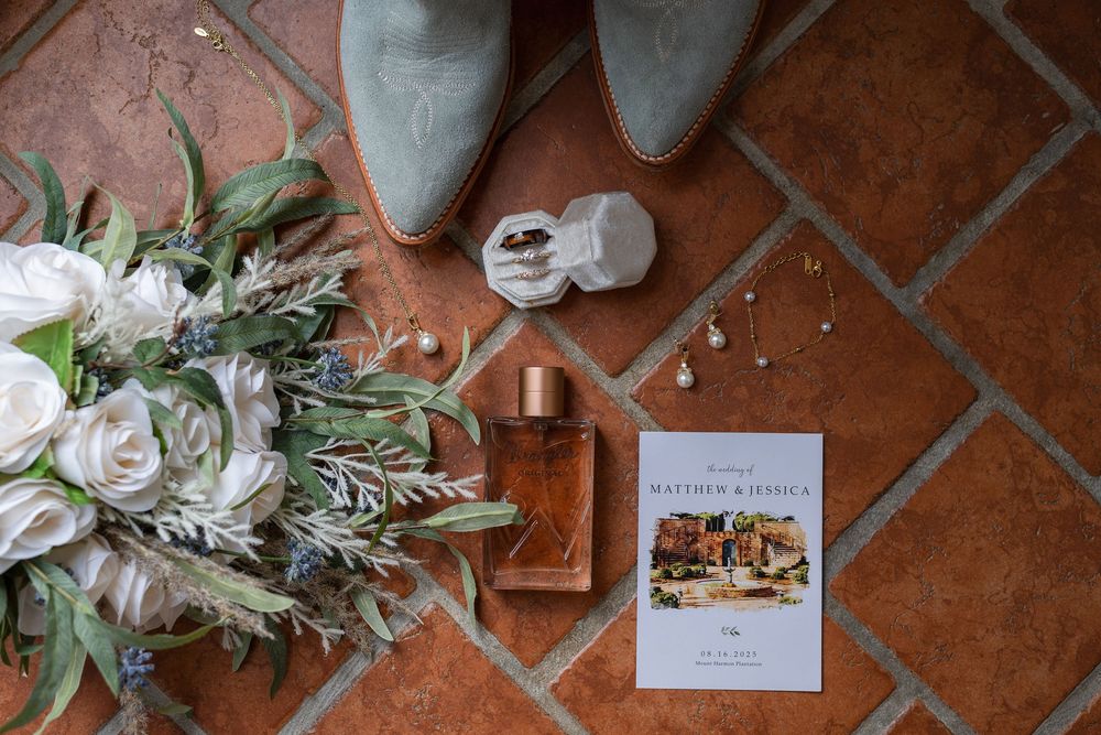 Wedding decorations and floral arrangements displayed on a terracotta tile floor with scattered rose petals and greenery.