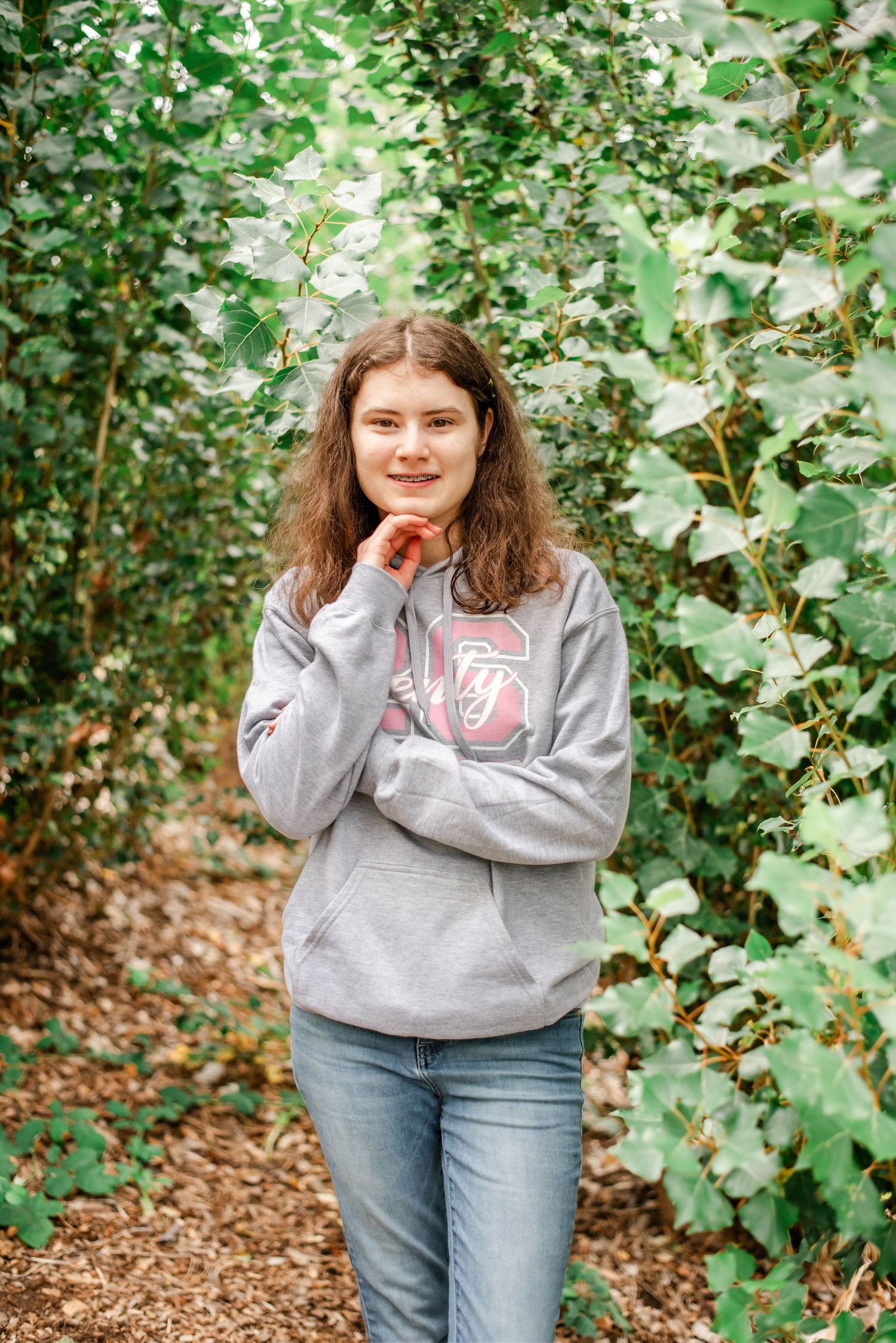 A series of outdoor portraits showing someone in a gray sweatshirt and jeans against a leafy green background.