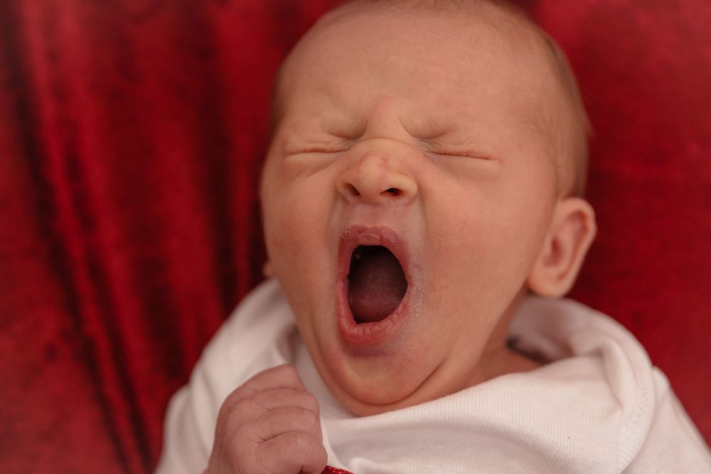 Series of photos showing a yawning newborn baby against a red background.