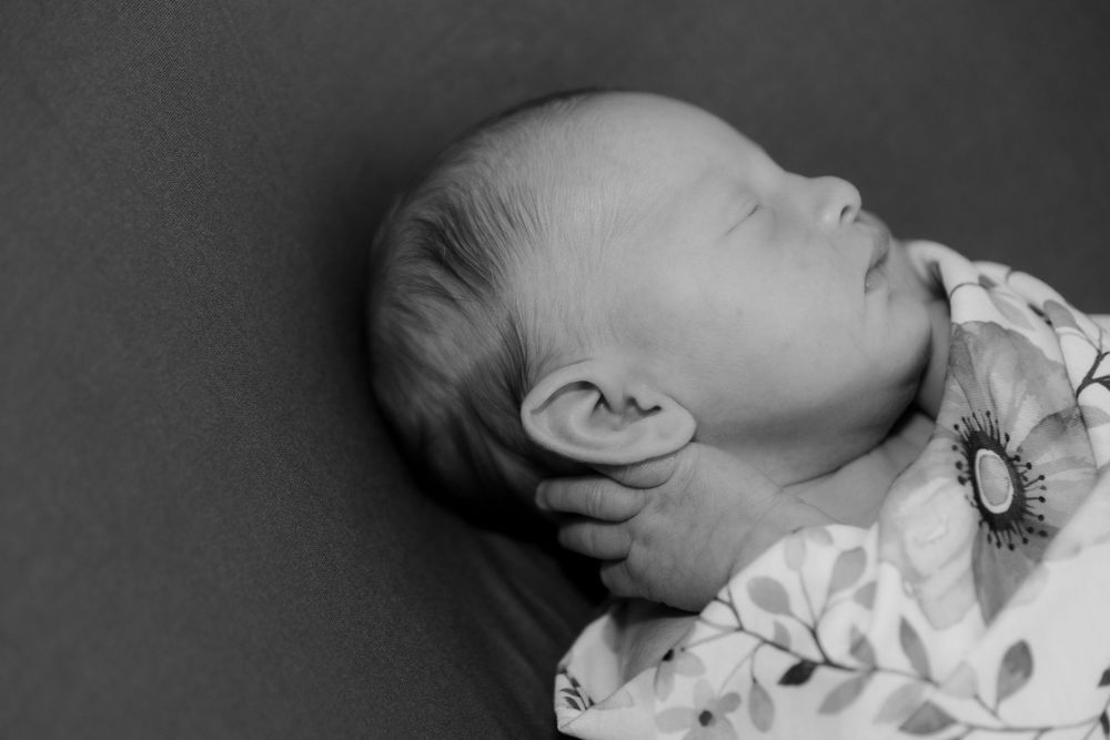 Black and white newborn photography with minimalist composition and soft shadows.