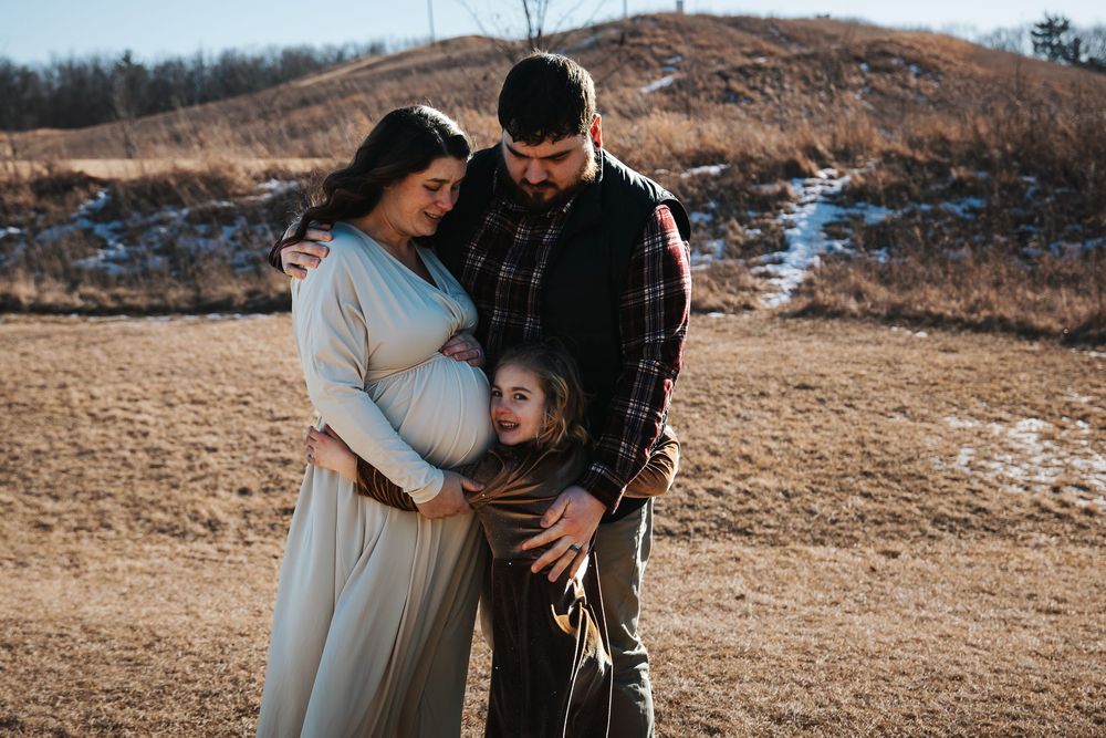 Intimate maternity photos captured against a natural hillside backdrop.