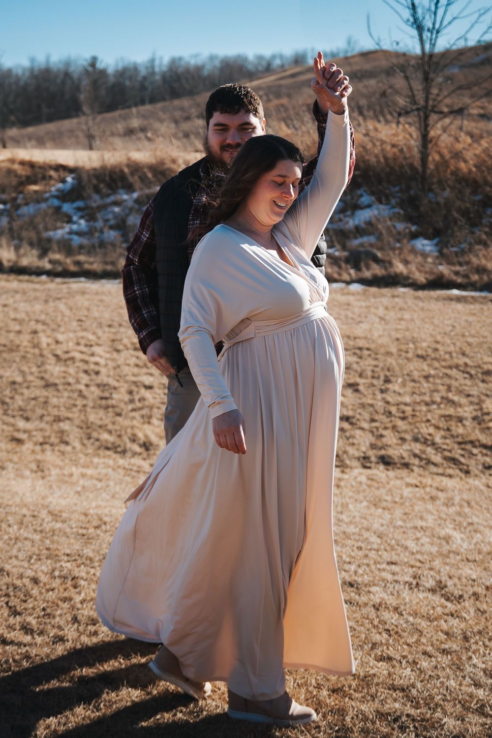 Dancing maternity portraits taken in a rustic outdoor setting.