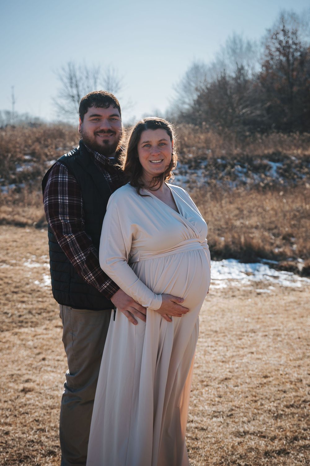 Joyful winter maternity session with natural landscape in the background.