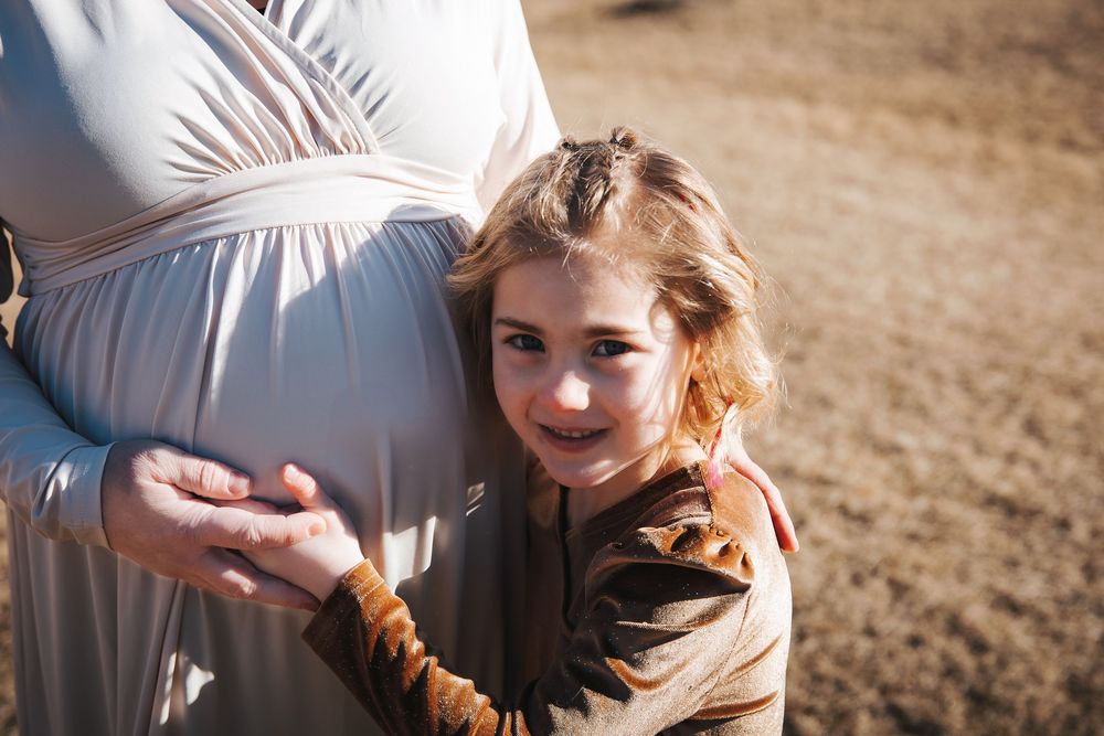 Outdoor maternity photography session in a natural setting with golden light.