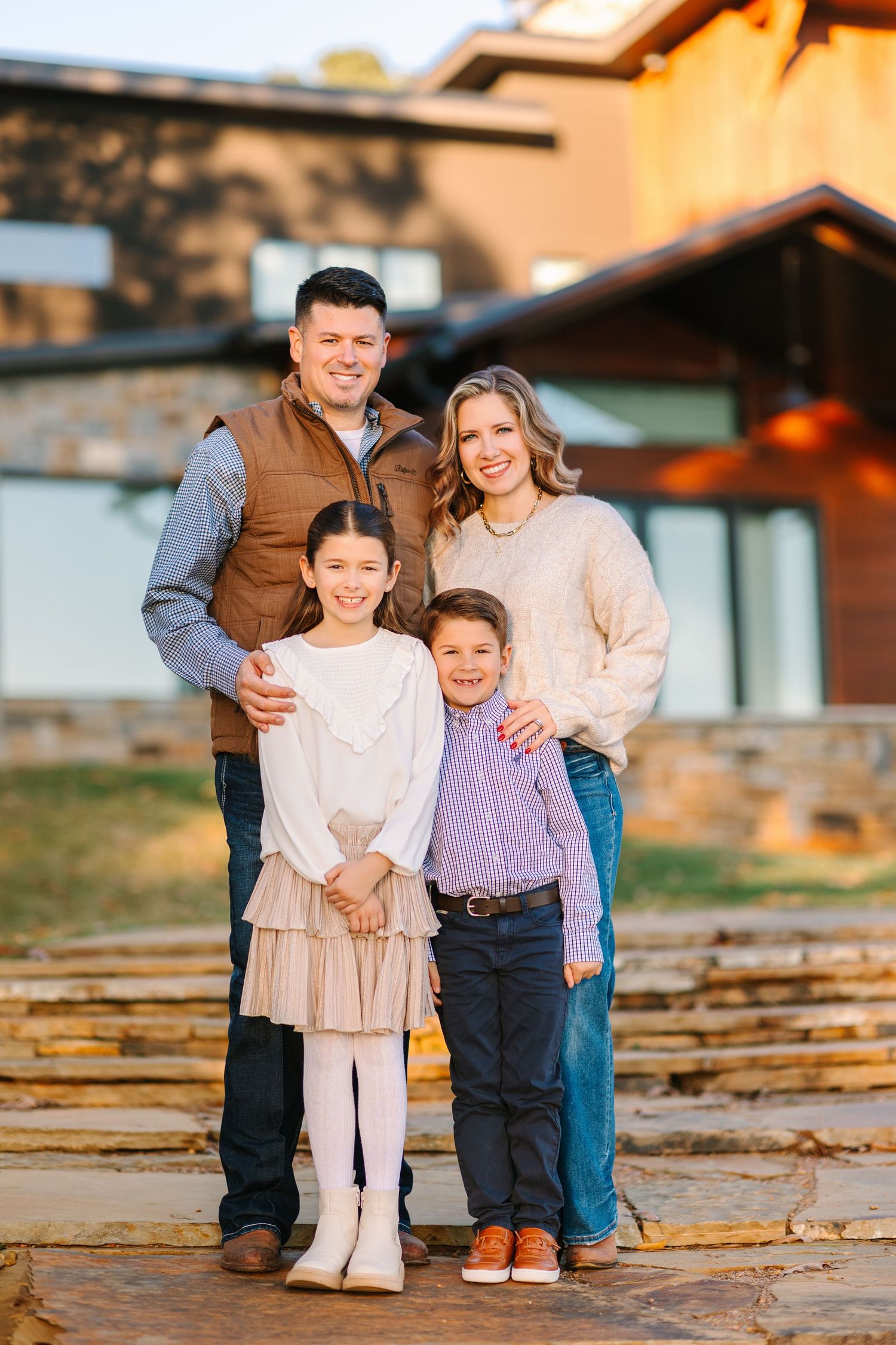Family sits together on wooden deck during golden hour autumn photoshoot at rustic cabin.